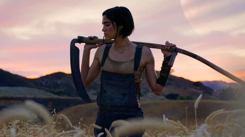Kora holding scythe in field